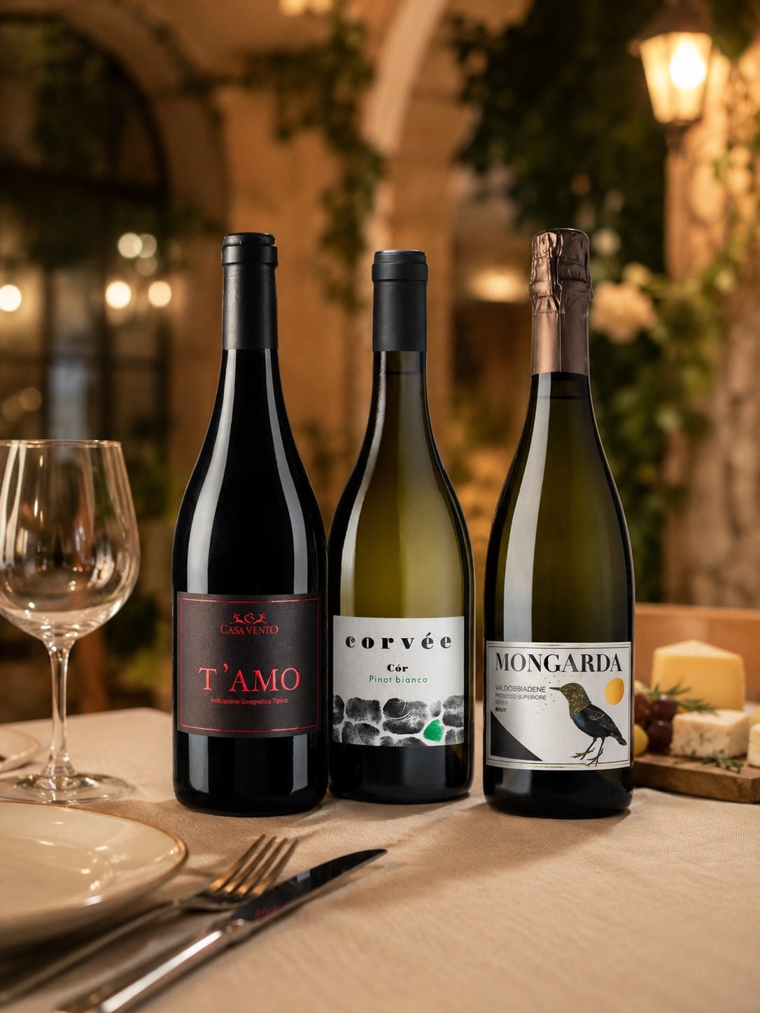 Three Italian wine bottles on an elegant table with an empty wine glass, cutlery, plate and cheese, set against a warm blurred Italian background.