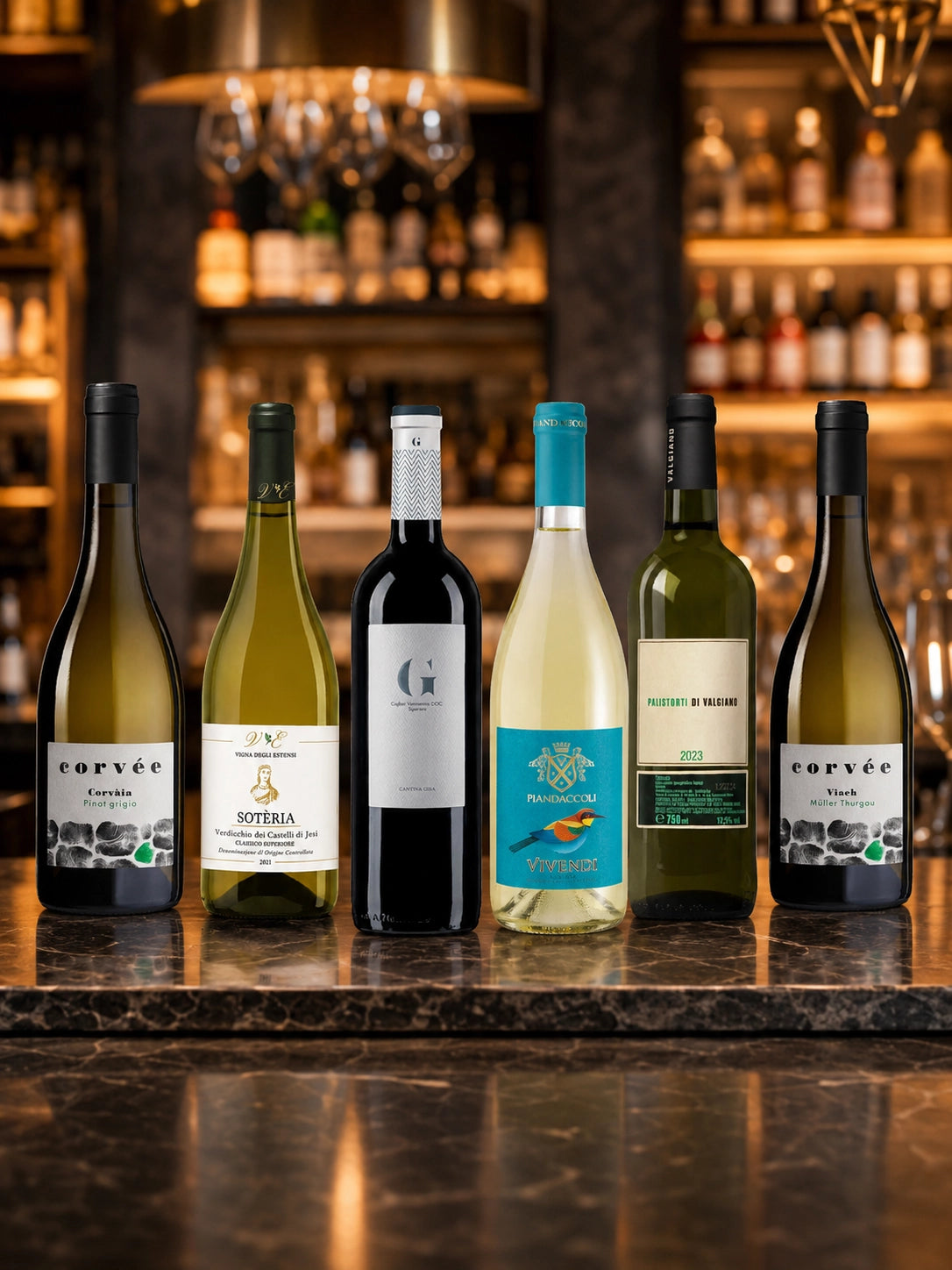 Six Italian white wine bottles from Fiorvino’s White Wine Discovery Pack displayed on an elegant wine bar table, featuring wines from Tuscany, Sardinia, Marche and Trentino.